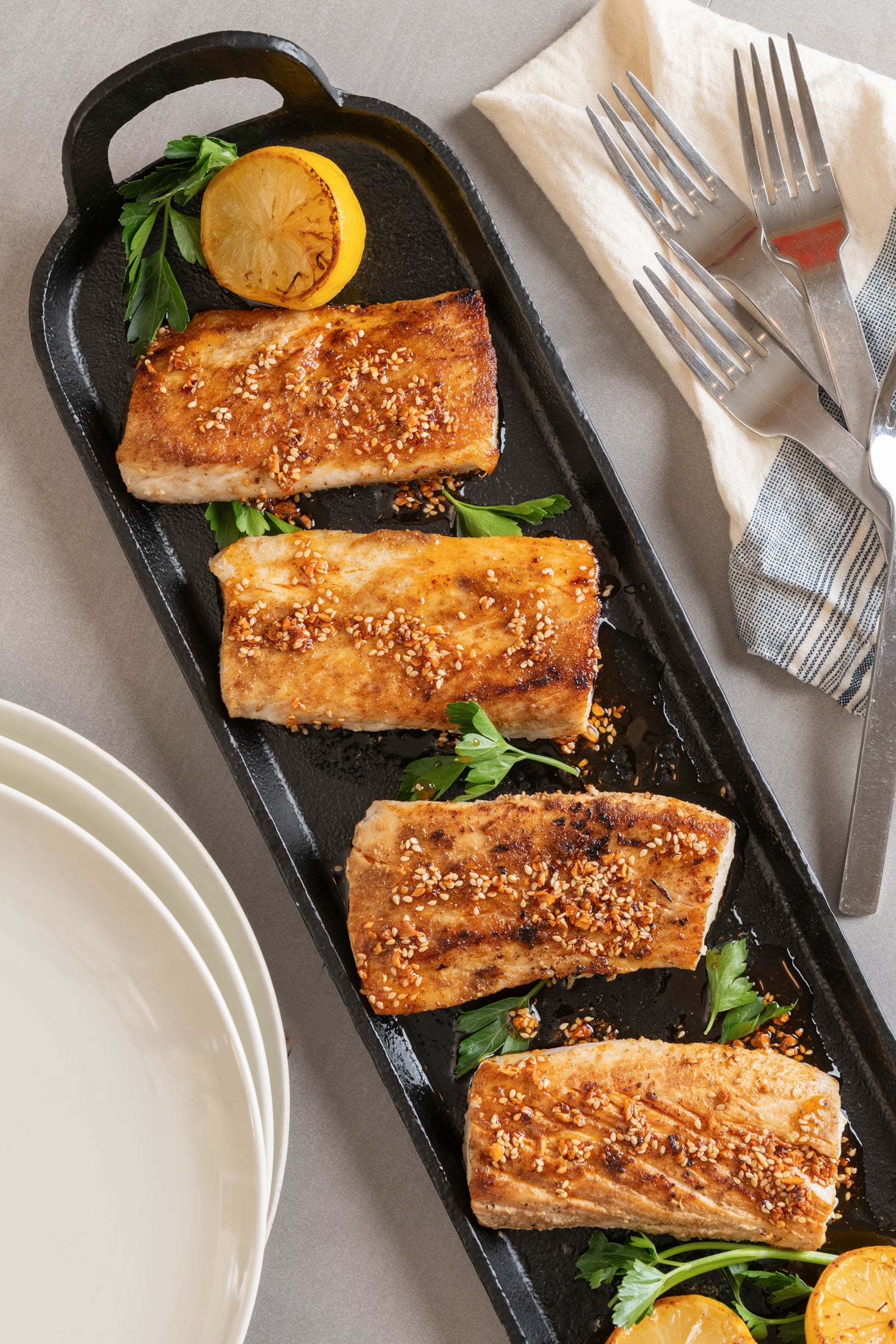 Ruby Crunch chili crisp over 4 pieces of grilled mahi mahi served on a cast iron platter garnished with grilled lemons and parsley