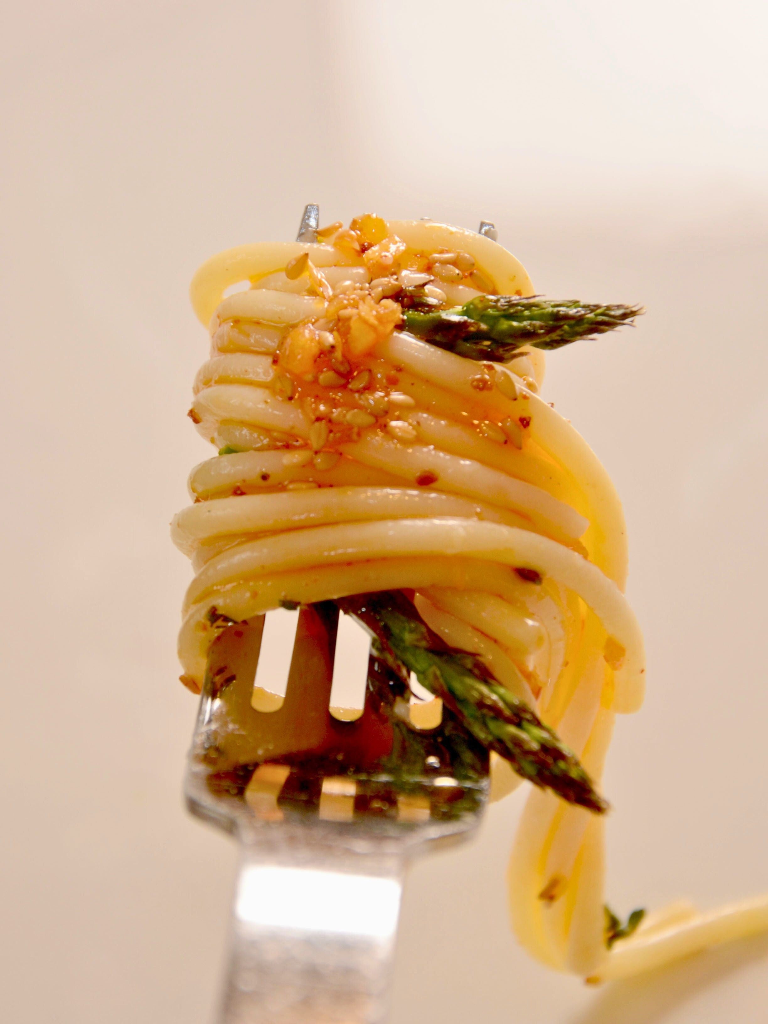 Pasta with a simple sauce of Ruby Crunch chili crisp and asparagus wrapped around a fork ready to be devoured