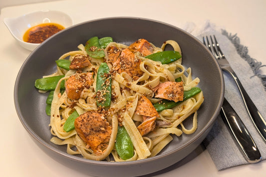 Plate of pasta, snow peas and salmon chunks dressed in Ruby Crunch chili crisp