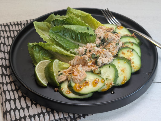 Plate of fresh lettuce with tuna salad and cucumbers topped with Ruby Crunch chili crisp