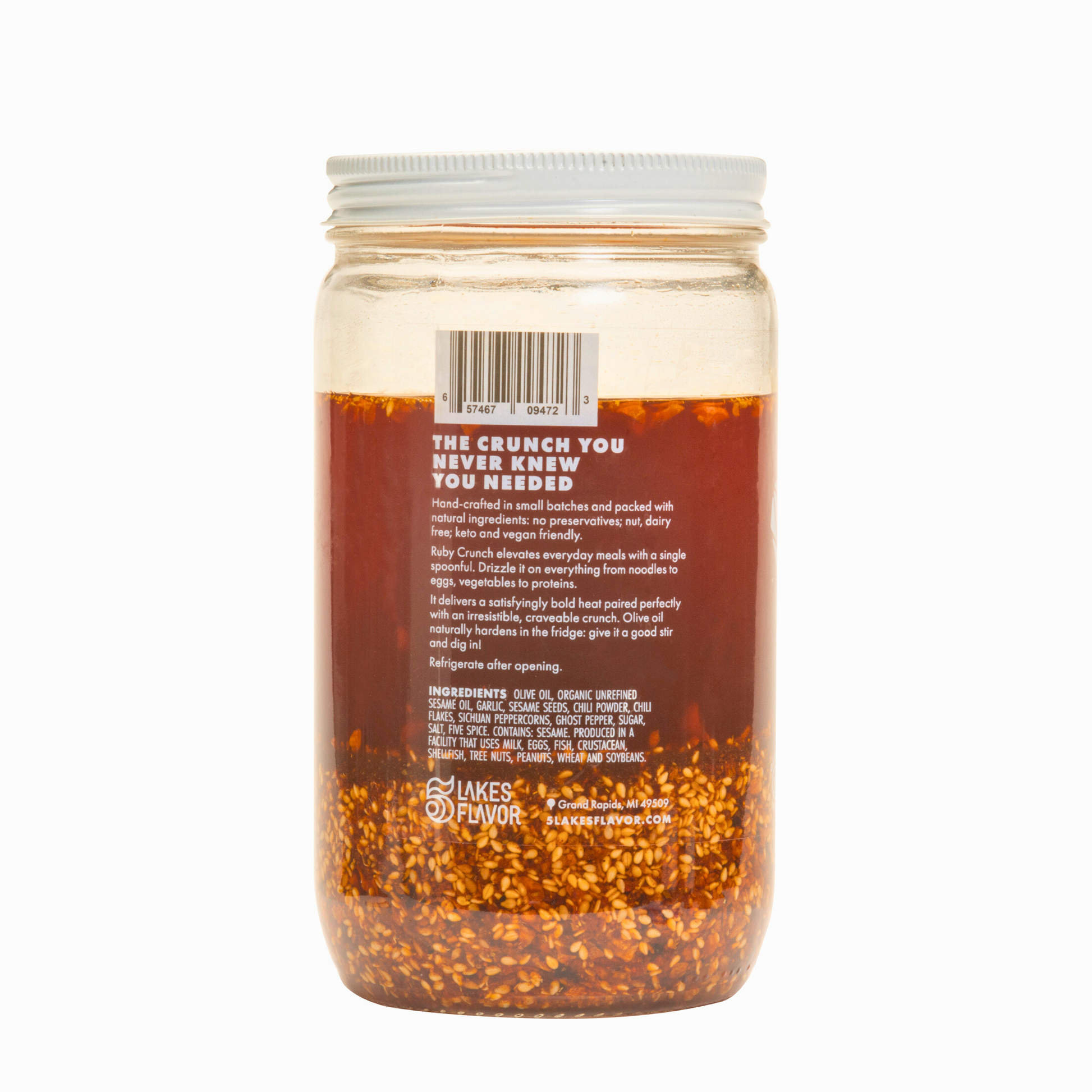 Side view of 32oz Spicy Ruby Crunch olive oil chili crisp hospitality jar, showing product description & ruby hued oil with crispy bits.